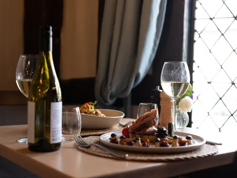 A meal and glasses of wine on a table beside a leaded window