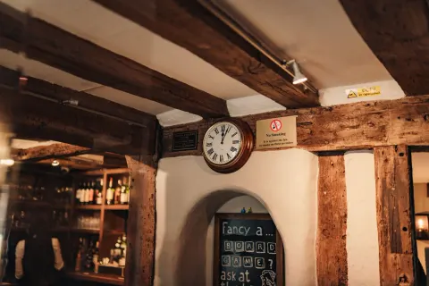 Exposed wooden beams above the bar and chalkboard