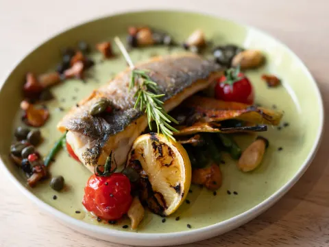 Fish served with potatoes, tomatoes and green vegetables
