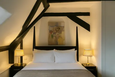 Double bed beneath the sloping beams of a heritage bedroom