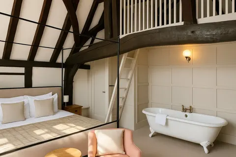 Suite with exposed beams, a freestanding bath and mezzanine balustrade