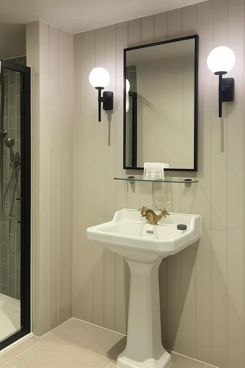Small washroom with a basin, mirror and dark tiled wall